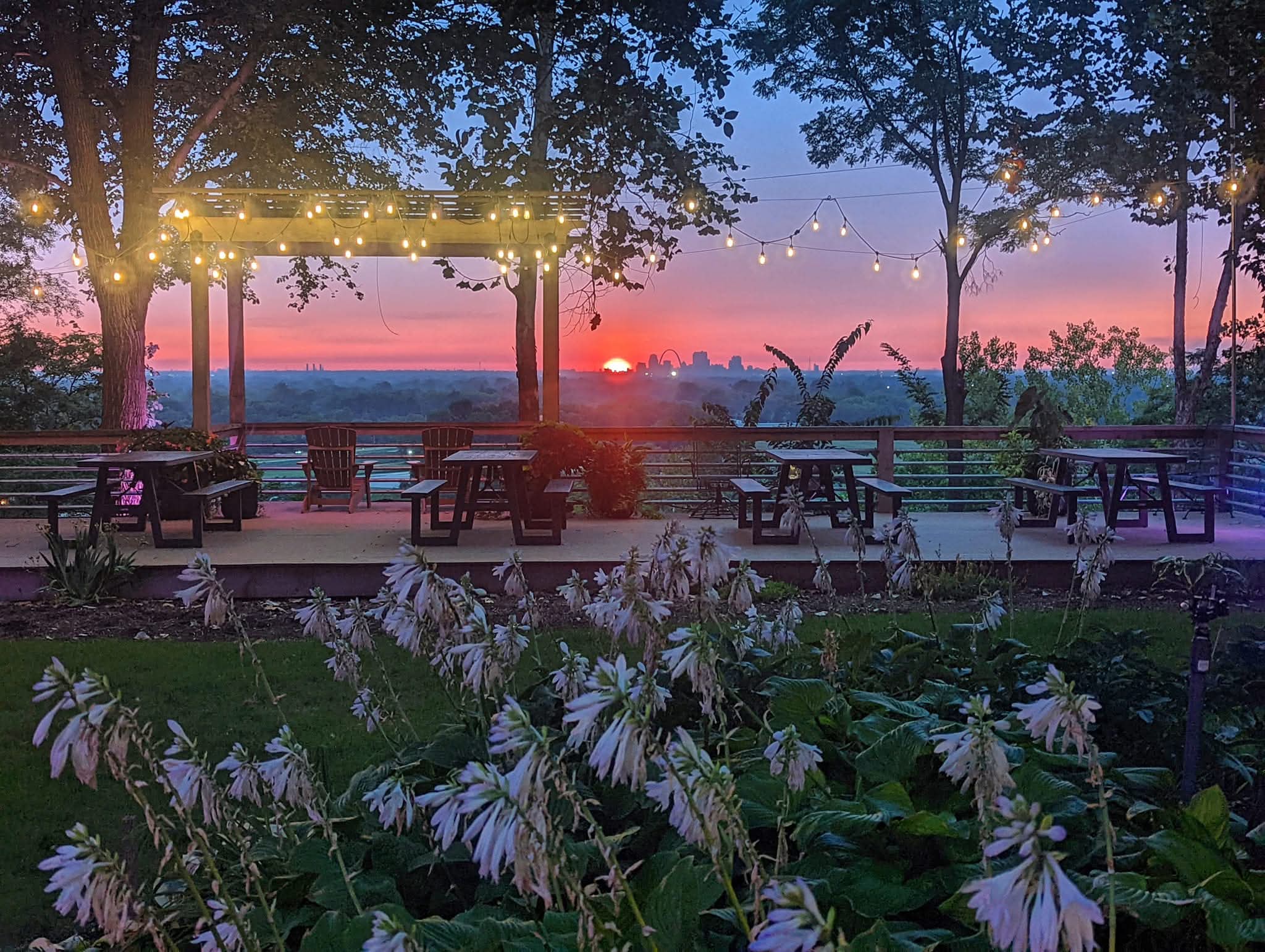 The garden deck at dusk with string lights and the St. Louis skyline